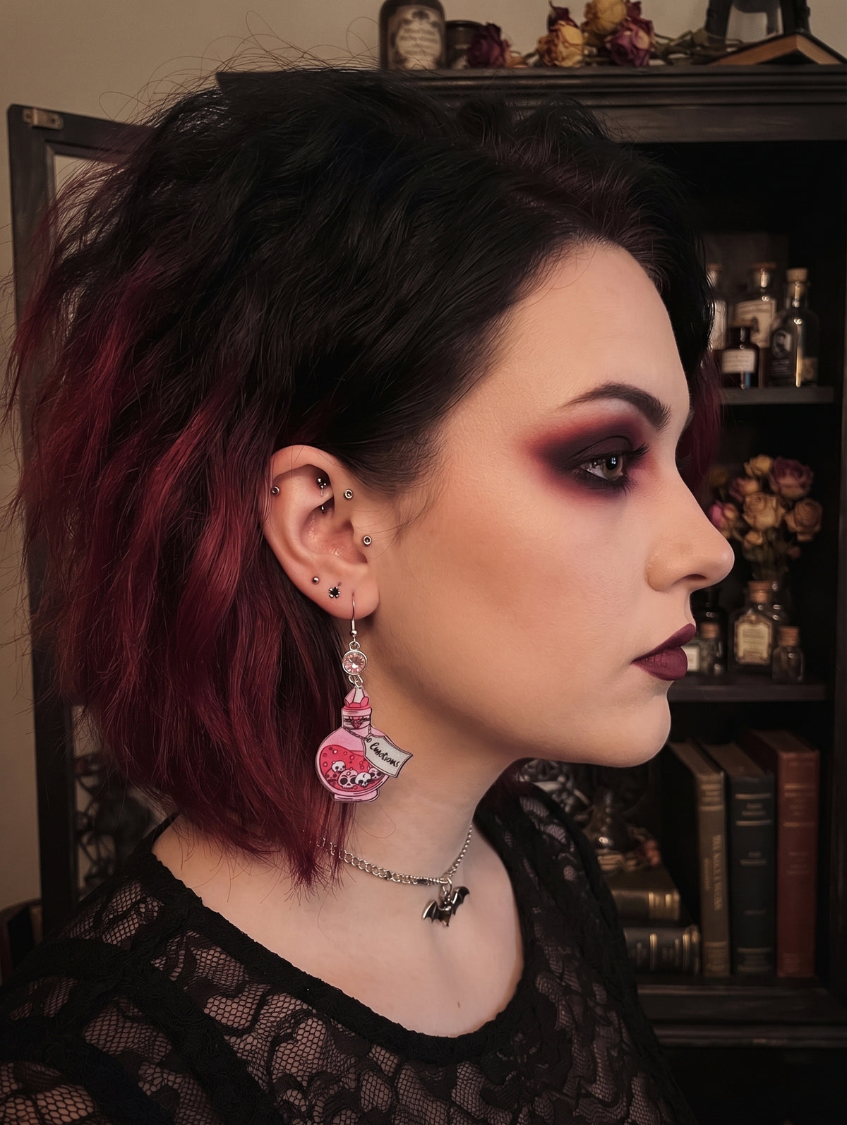 AI generated model wearing the pink Emotions potion bottle earring, styled goth aesthetic, not a real person
