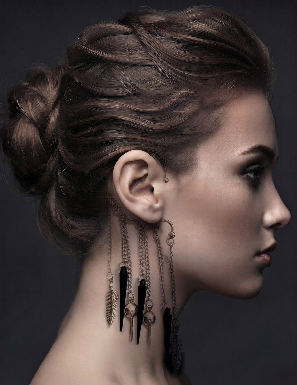 Side profile of a model with dark braided hair wearing the silver bird skull ear cuff, with multiple chains and black charms dangling alongside the side of her neck.