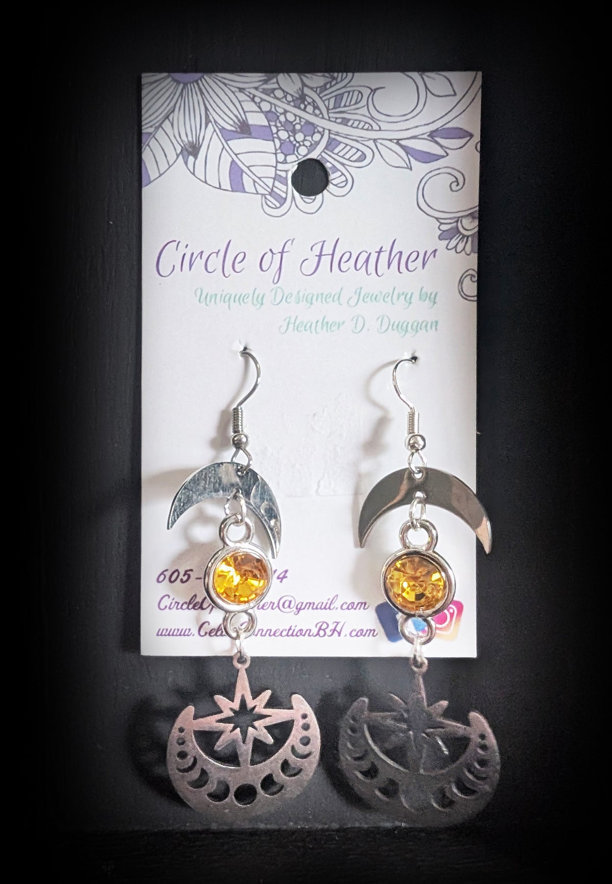 Celestial Sparkling Earrings by Circle of Heather, brushed silver crescent moons above faceted golden stones and cut metal discs with star and moon phase detail, shown on the branded Circle of Heather card.