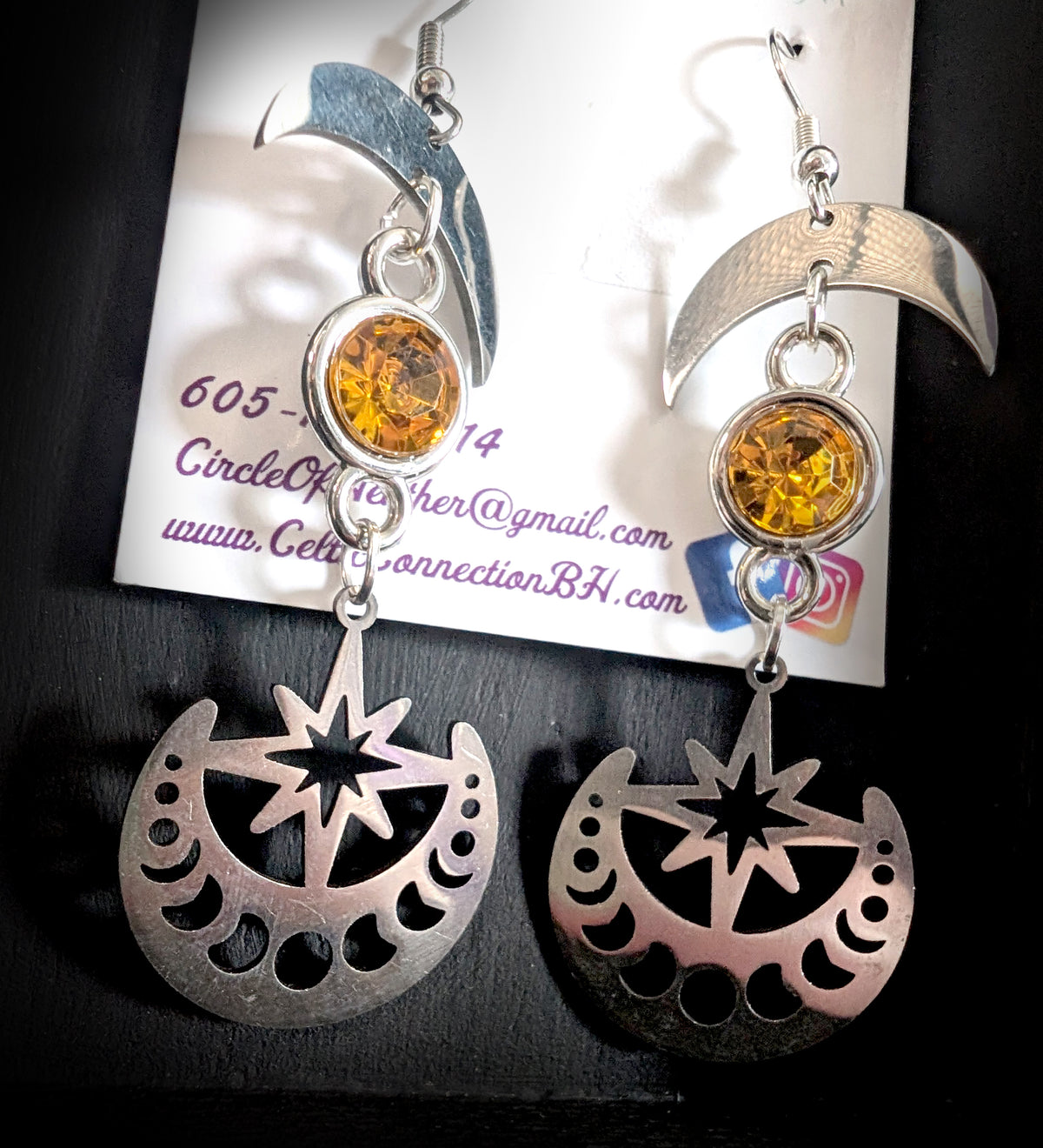 Celestial Sparkling Earrings by Circle of Heather, angled close-up showing the faceted golden stone in its silver bezel and the eight-point star cut into the moon phase disc, shown on the branded Circle of Heather card.