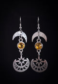 Celestial Sparkling Earrings by Circle of Heather, full view of both earrings showing the crescent moon top, golden stone and cut star and moon phase disc, on a plain black background.