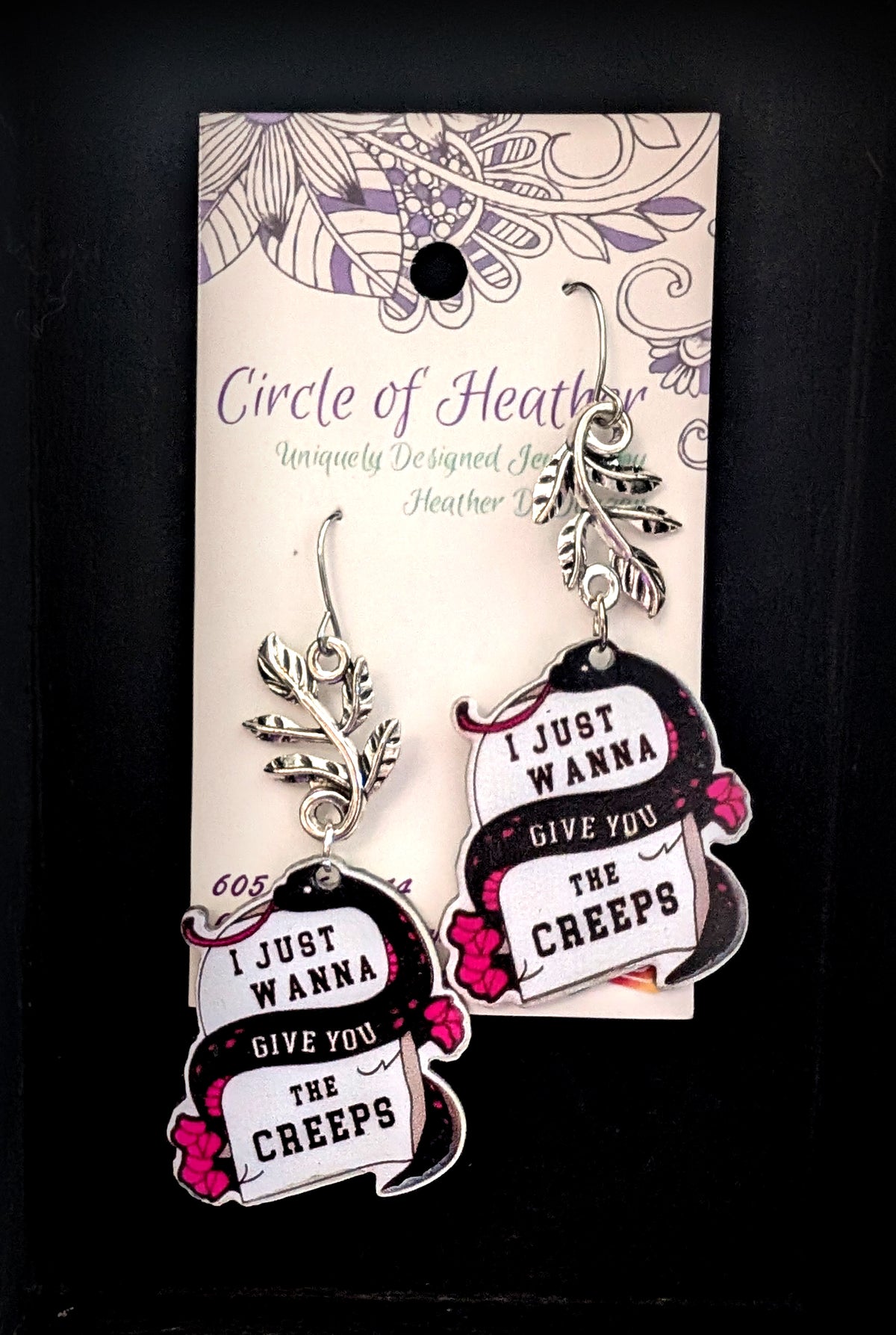 Wanna Give You The Creeps Earrings by Circle of Heather, angled close-up showing the black snake, lettering and hot pink floral detail, shown on the branded Circle of Heather card.