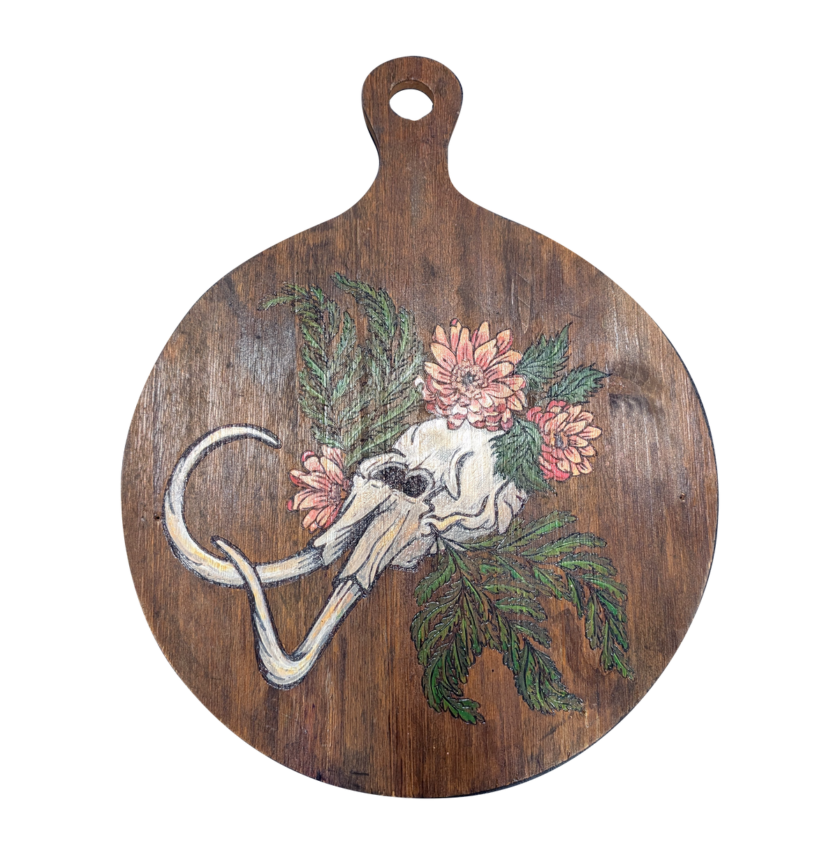 Another view of Dystopian Cyclopean by CamiThunderInk, an original pyrography and paint piece on a reclaimed round wood paddle showing a one eyed skull with tusks among pink chrysanthemums and green cedar