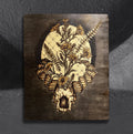 Flora Capricora by CamiThunderInk, an original pyrography, watercolor, and stain painting on pine of a horned goat skull bursting into sunflowers and botanicals in front of a moon, on a stippled black background