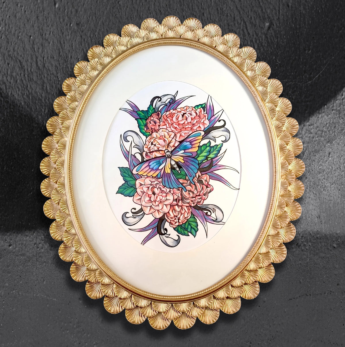 Flutter over Camellias by CamiThunderInk, an original ink and alcohol marker drawing of a colorful moth among camellias and ornamental scrollwork, in a gold scalloped oval frame