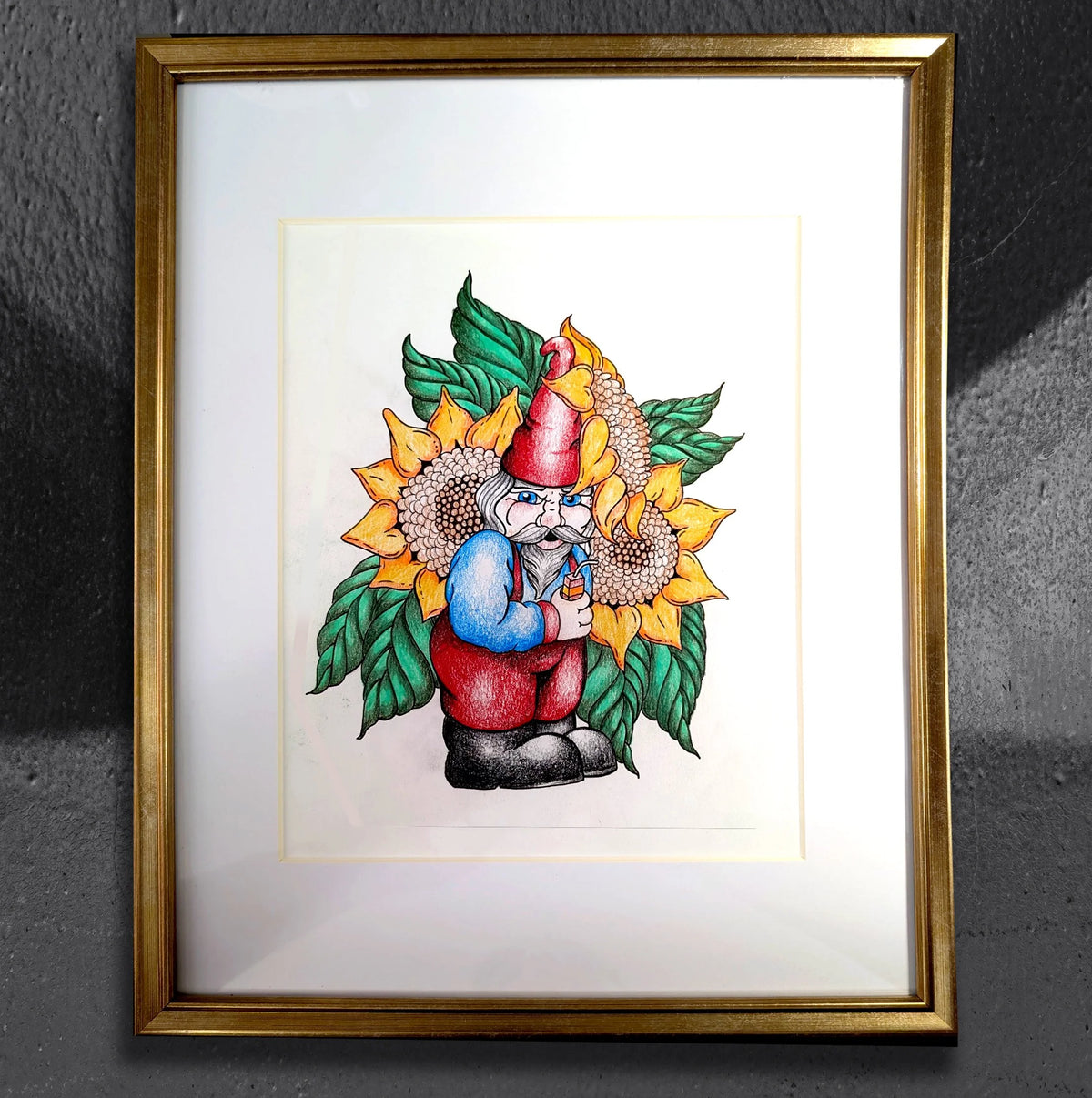 Gnome-eous Interruptus by CamiThunderInk, an original colored pencil and ink drawing of a grumpy gnome with a juice box in front of sunflowers, matted in a gold frame