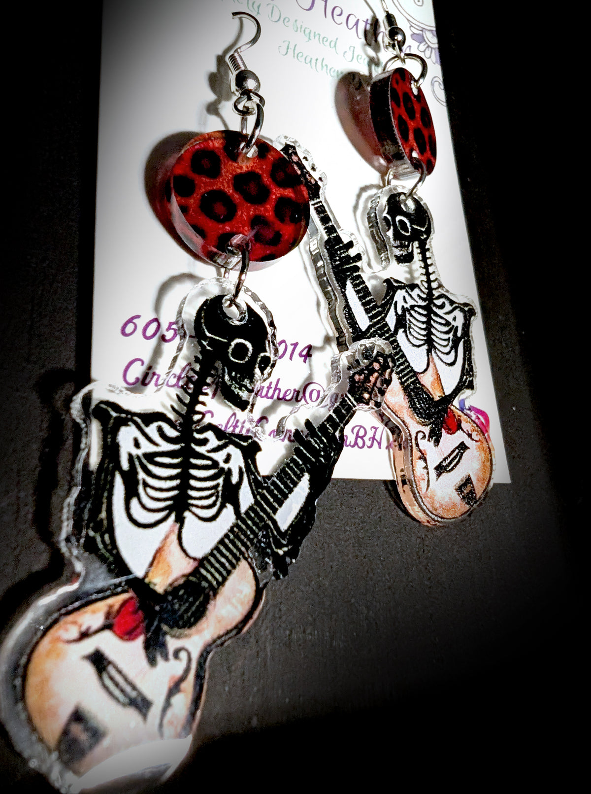 Guitar Ghoul Earrings by Circle of Heather, angled close-up showing the skeleton ribcage detail and guitar artwork, shown on the branded Circle of Heather card.