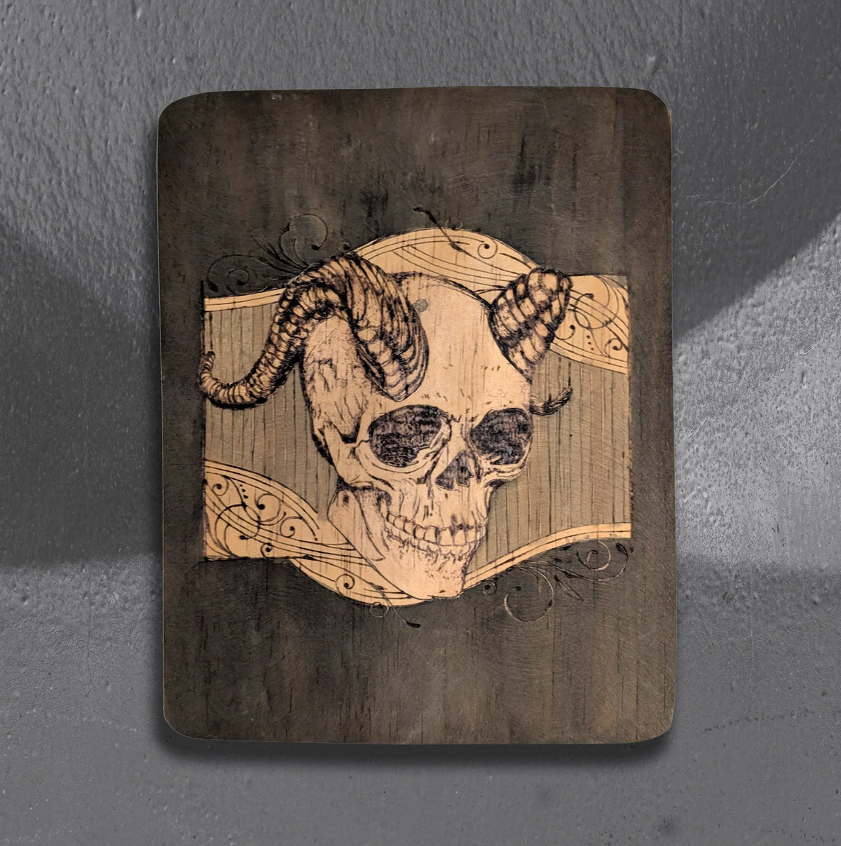 Cerebral Cernunnos by CamiThunderInk, an original pyrography piece on a rustic reclaimed wood slab showing a horned skull against a heavily textured burned background