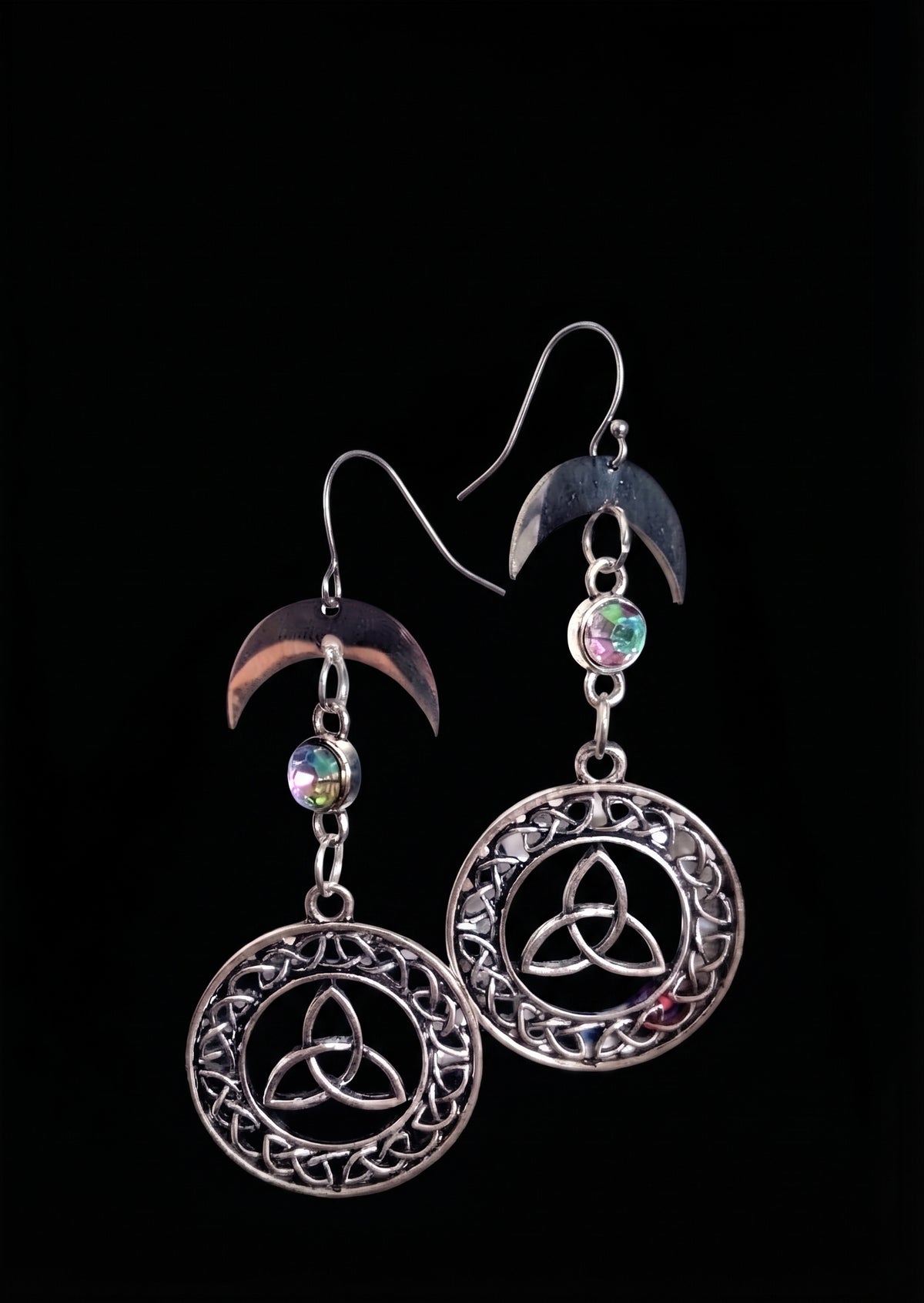 Knotted Luna Trinity Earrings by Circle of Heather, full view of both earrings showing the crescent moon, iridescent faceted stone and trinity knot inside the knotwork medallion, on a plain black background.