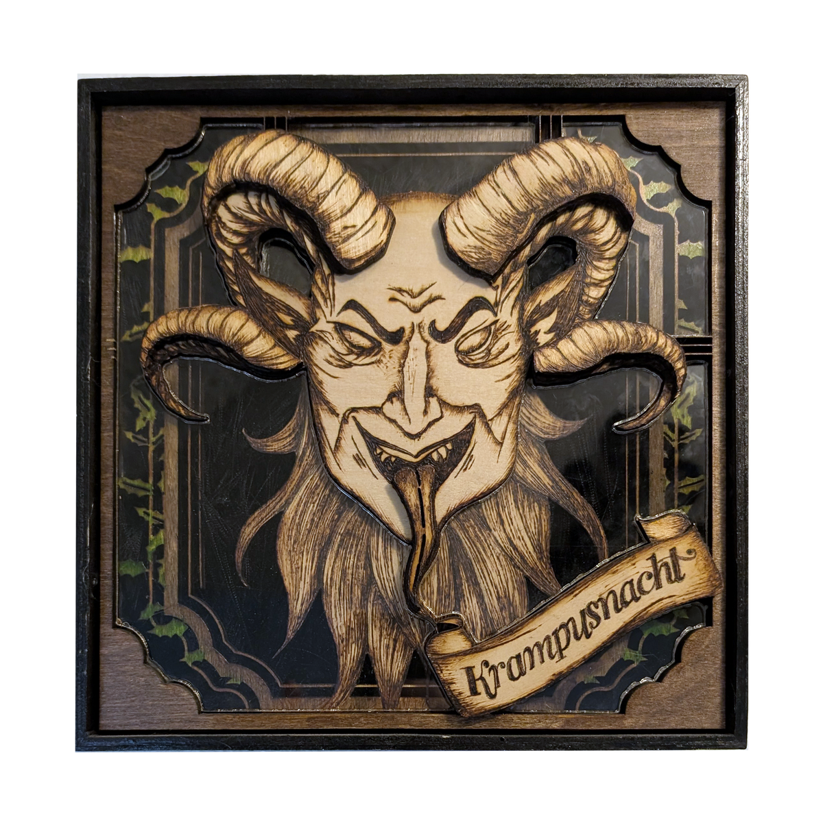 Another view of Krampusnacht by CamiThunderInk, an original layered relief of Krampus made from laser cut wood and acrylic, with pyrography, watercolor, stain, and real black feathers, in a recycled frame