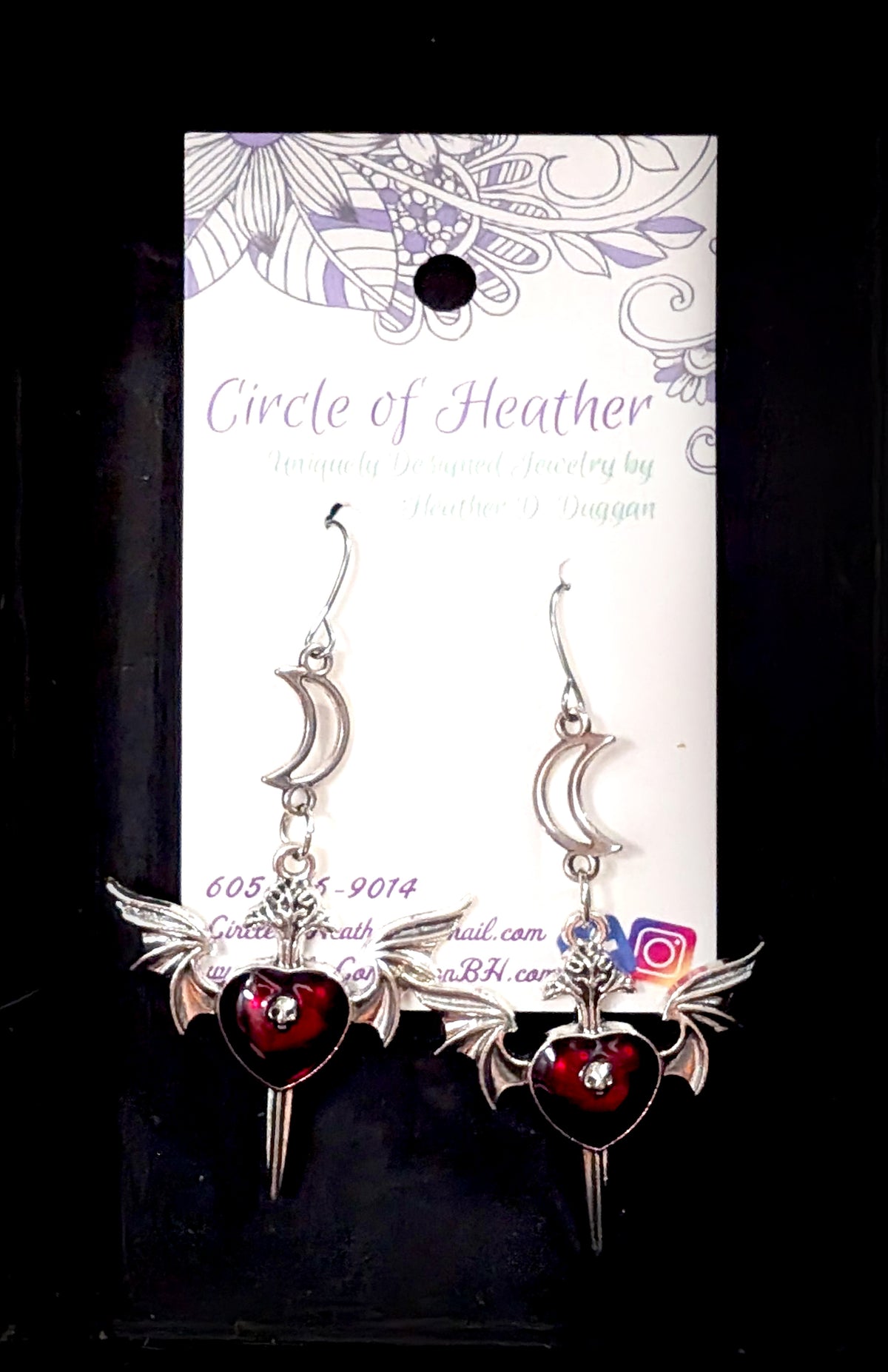 Silver dagger earrings with bat wings, deep red enamel hearts set with clear crystals, hanging from crescent moon charms