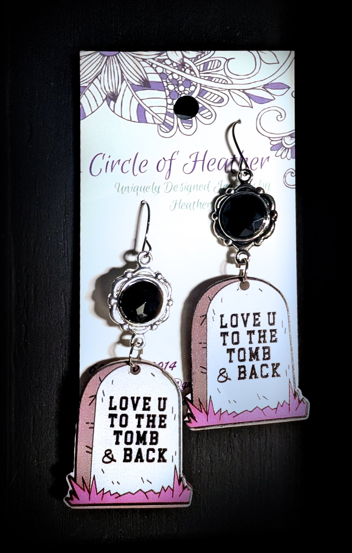 Love U to the Tomb and Back Earrings by Circle of Heather, angled close-up of the faceted black stones and printed headstone charms with pink grass detail, shown on the branded Circle of Heather card.