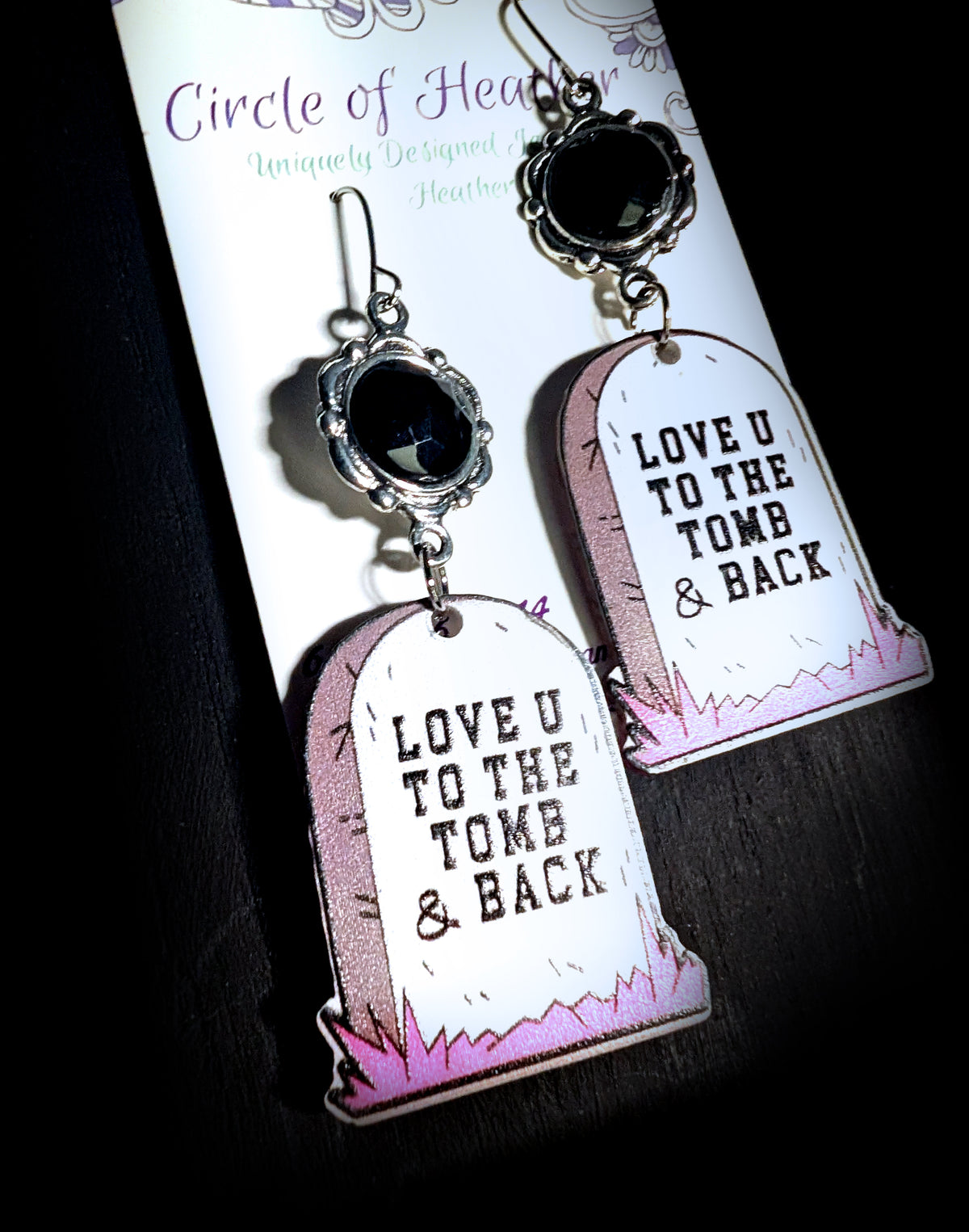 Love U to the Tomb and Back Earrings by Circle of Heather, full view of both earrings showing the black stone tops and pale blue headstone charms with hot pink grass, on a plain black background.