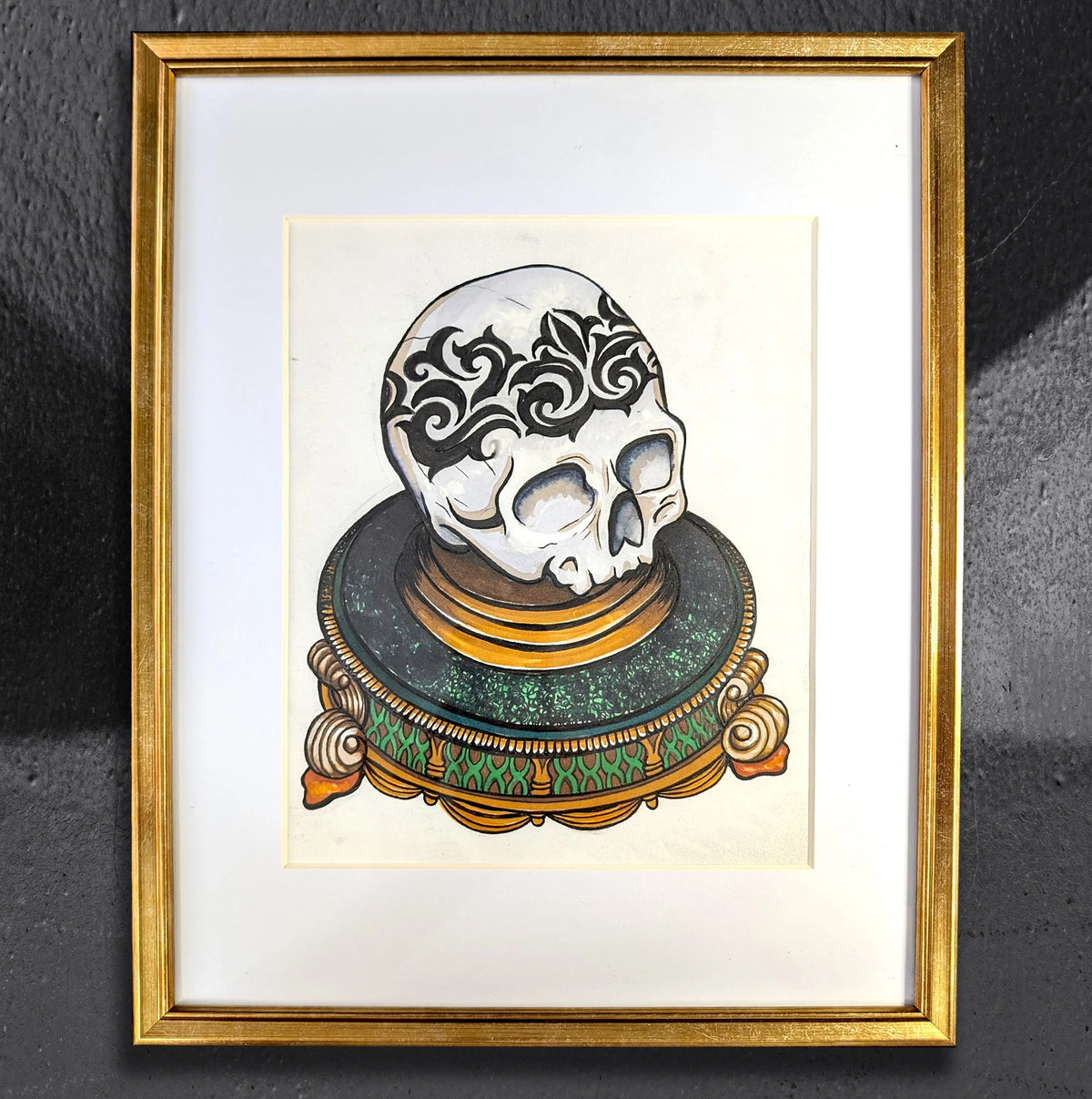 Ornamental Skull on a Platter by CamiThunderInk, an original ink and alcohol marker drawing on cream paper of a decorative skull on an ornate geometric platter, matted in a gold frame