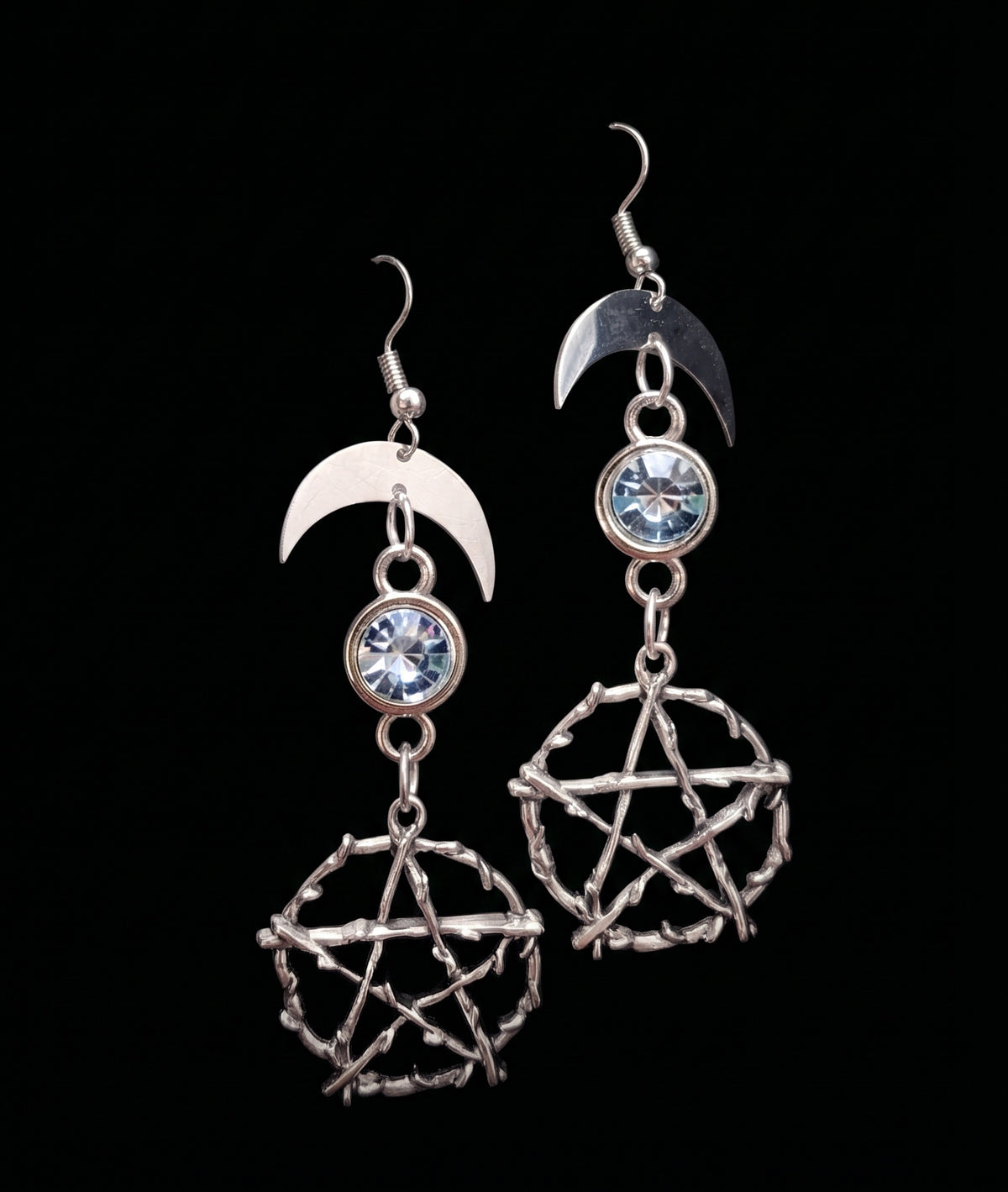 Pentacle Lunar Blue Blush Earrings by Circle of Heather, full view of both earrings showing the crescent moon, pale blue stone and the branch texture on the pentacles, on a plain black background.