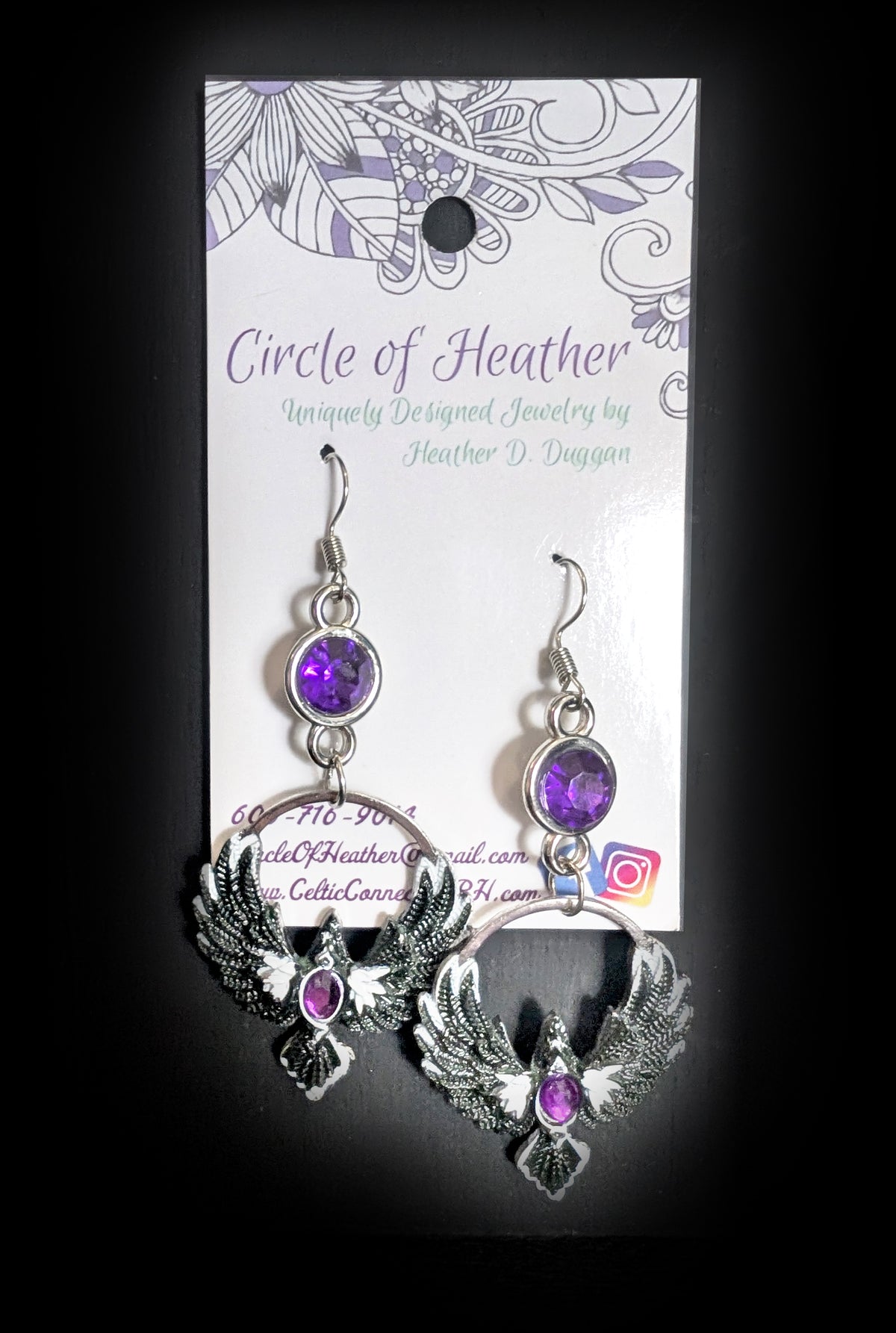 Purple Phoenix Halo Earrings by Circle of Heather, faceted purple stones above open silver circles with winged bird charms and purple chest stones, shown on the branded Circle of Heather card.