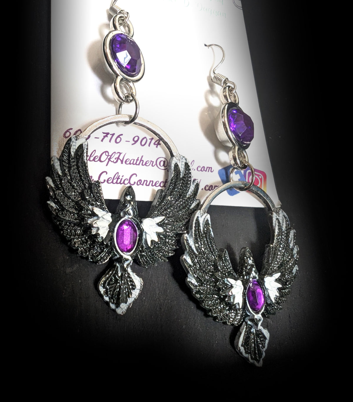 Purple Phoenix Halo Earrings by Circle of Heather, angled close-up showing the feather detail on the wings and the oval purple stone at the bird's chest, shown on the branded Circle of Heather card.