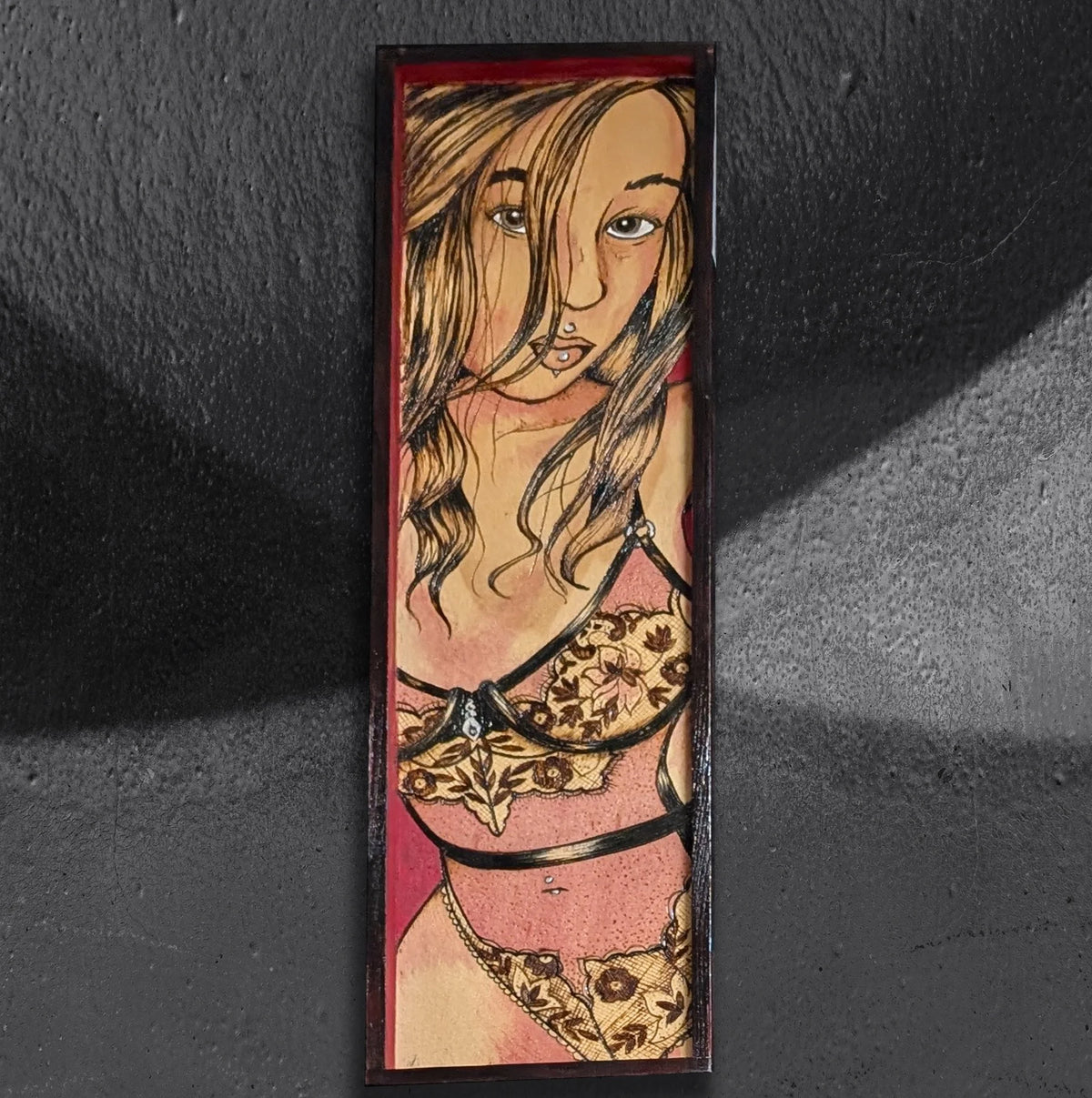 Another view of Sensational In Scarlet 3 by CamiThunderInk, an original pyrography, watercolor, and acrylic painting on wood showing a close up of a figure with loose waves, facial and body piercings, lace lingerie, and black harness straps, set against a scarlet background