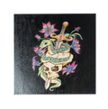 Serenum Serpentis by CamiThunderInk, an original pyrography, watercolor, and acrylic painting on wood showing an emerald green serpent coiled around a skull pierced by a dagger, with pink and purple flowers on a black background