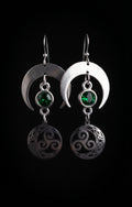 Shimmer Lunar Nocturne Earrings by Circle of Heather, full view of both earrings showing the wide crescent moons, green stones and triple spiral medallions with Celtic knotwork, on a plain black background.