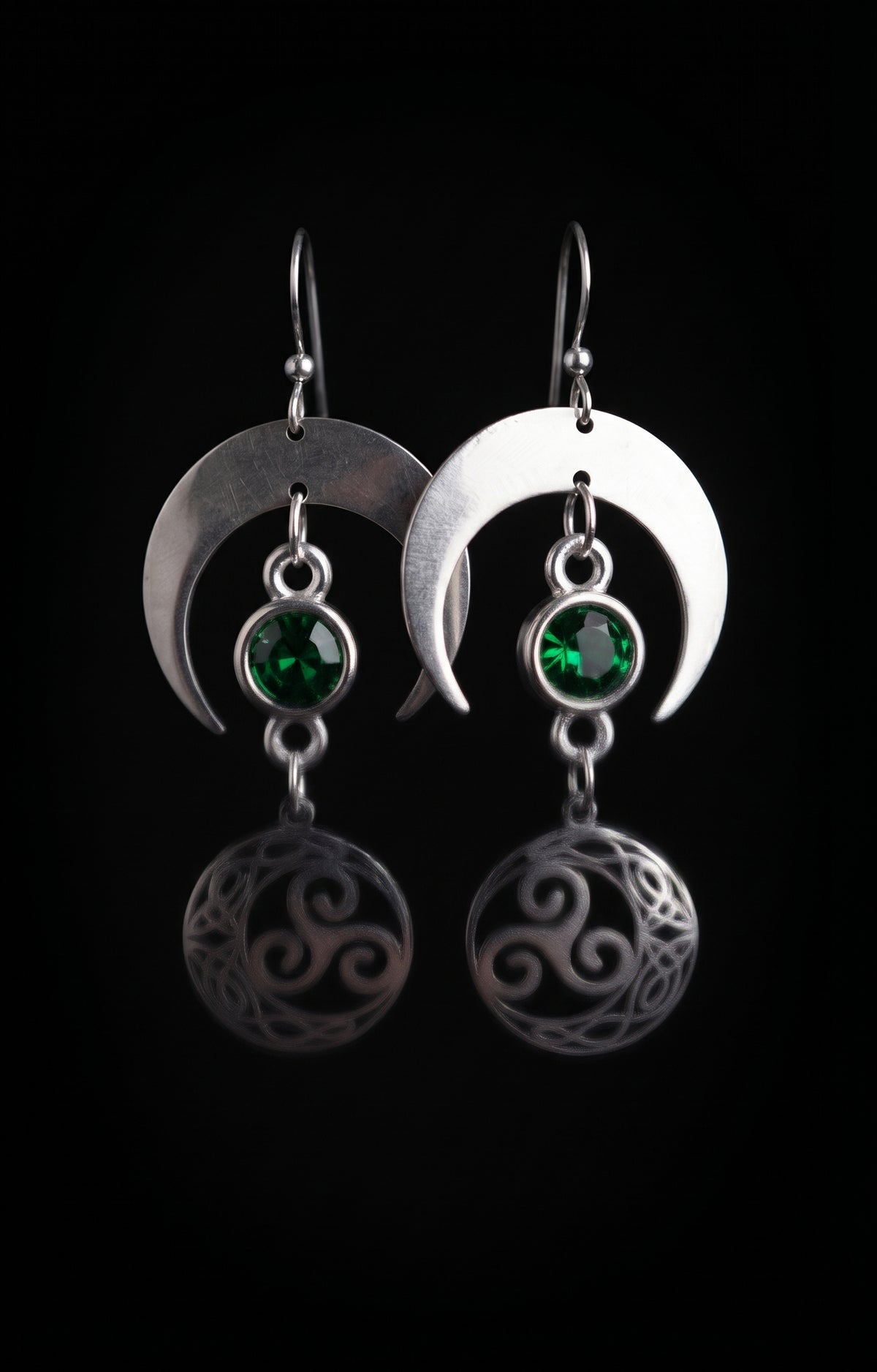 Shimmer Lunar Nocturne Earrings by Circle of Heather, full view of both earrings showing the wide crescent moons, green stones and triple spiral medallions with Celtic knotwork, on a plain black background.