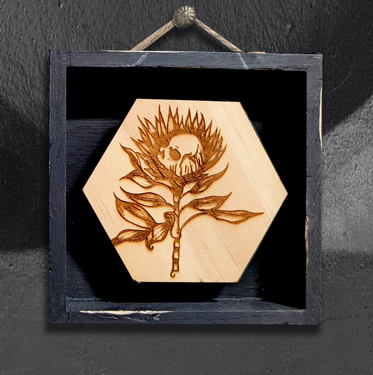 Skully Flowers Protea miniature framed piece by CamiThunderInk, a laser etched wood protea with a skull at its center, in a small 4x4 frame