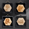 Skully Flowers miniature framed series by CamiThunderInk, laser etched wood botanical illustrations with a skull at the center of each flower, in small 4x4 frames, showing all four designs: dahlia, rose, protea, and lotus