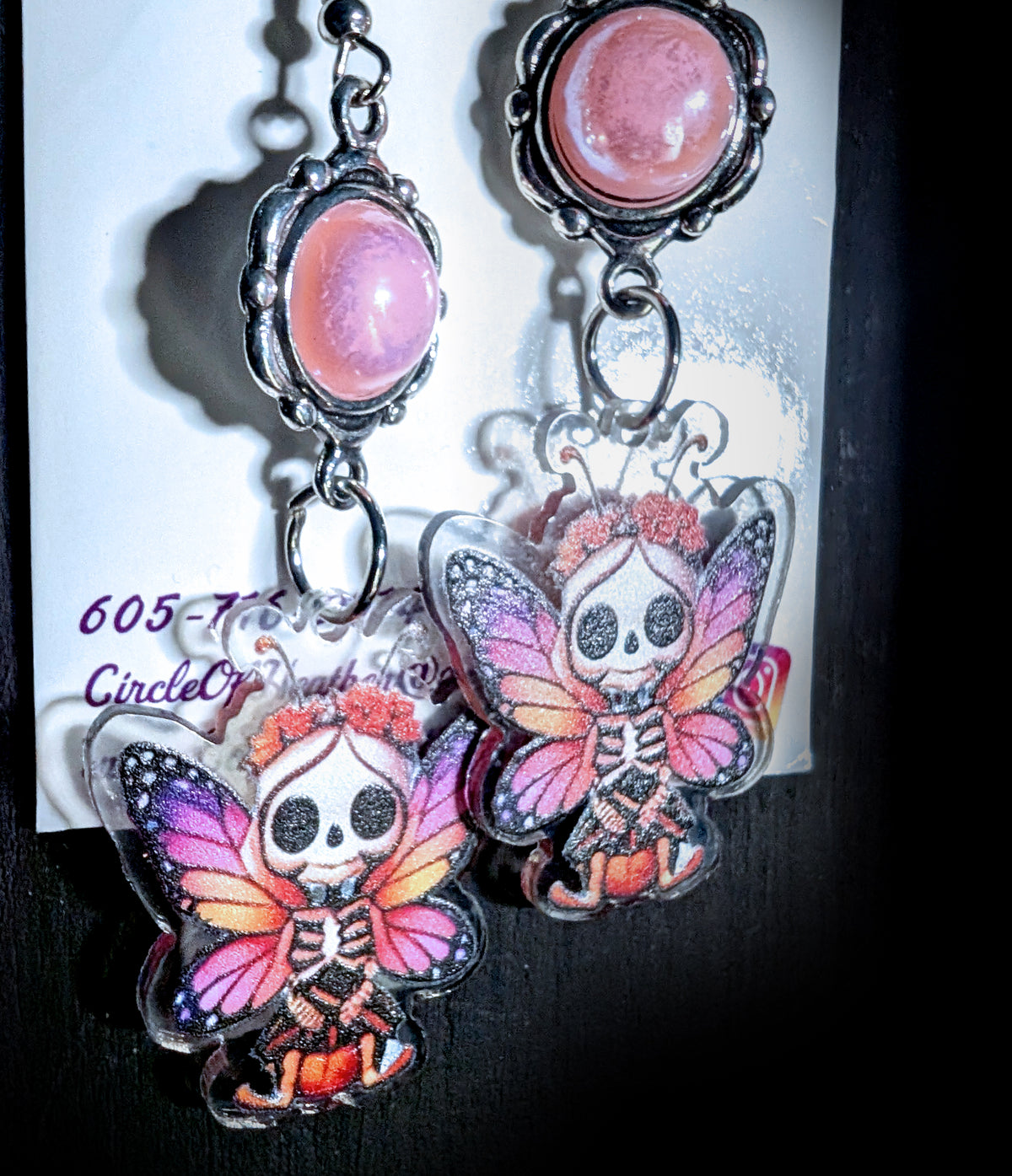 Sweet Pink Skull Fairy Earrings by Circle of Heather, angled close-up showing the beaded silver-tone bezels around the pink cabochons and the skeleton ribcage detail on the fairy charms, shown on the branded Circle of Heather card.