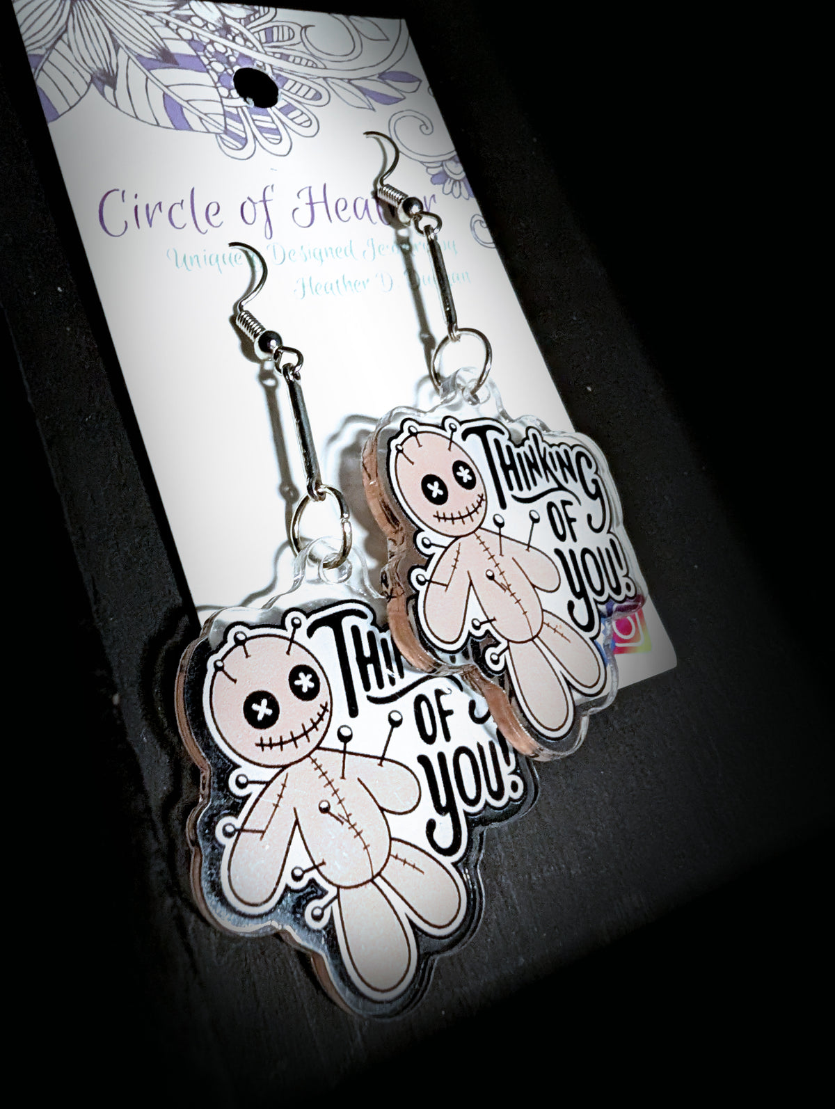 Voodoo Doll Thinking of You Earrings by Circle of Heather, angled close-up showing the pin and stitch detail on the printed voodoo doll charms, shown on the branded Circle of Heather card.