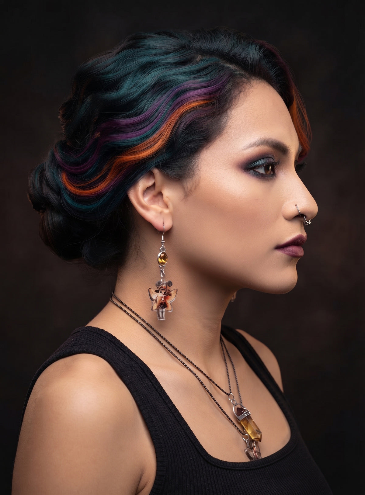 Witchy Skull Fairy Earrings by Circle of Heather worn by a model with teal, purple and orange hair in an updo, amber stone above a printed skull fairy charm in a black witch hat with orange wings.