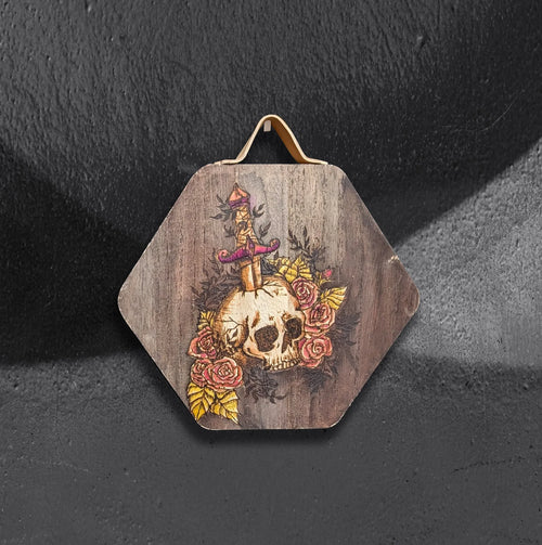 Arthur's Rosy Relic by CamiThunderInk, an original pyrography and watercolor piece on solid wood showing a skull pierced by a dagger and surrounded by bright pink roses