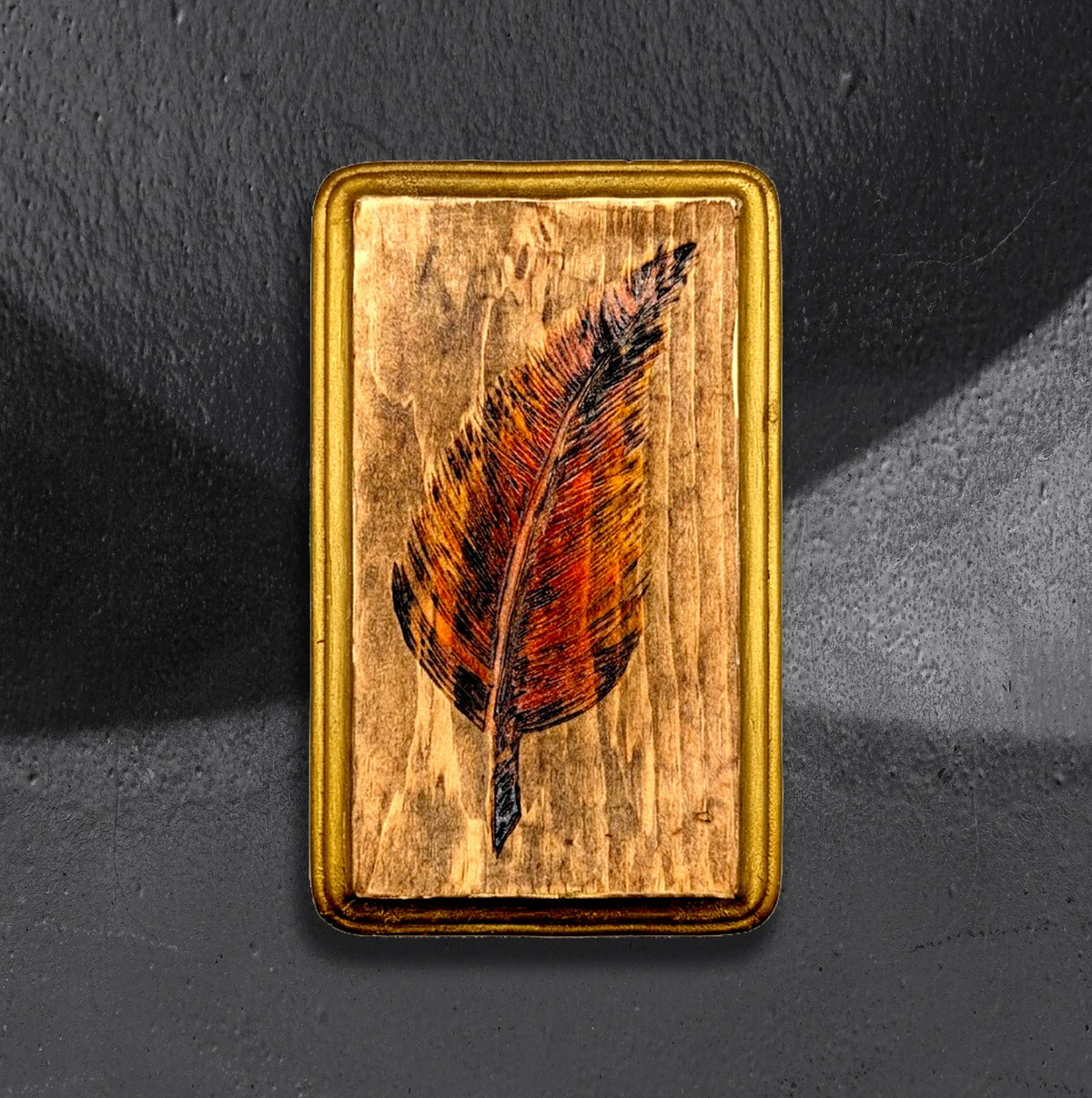 Feather flash block by CamiThunderInk, a small reclaimed pine block with a burned and painted feather in auburn tones, with gold edging