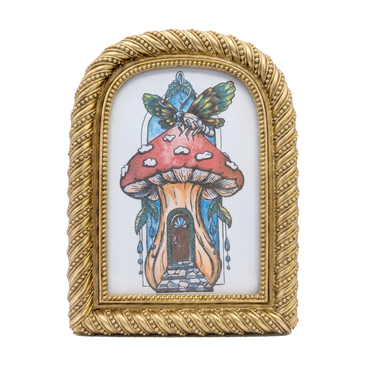 Another view of Mushie House framed print by CamiThunderInk, a whimsical mushroom cottage illustration topped with a winged insect, in a small arched gold frame with rope and bead trim