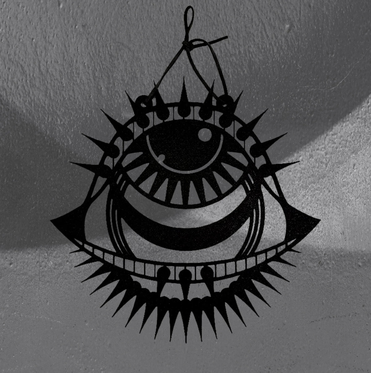Punk Evil Eye wall hanger by CamiThunderInk, a matte black 3D printed eye with a spiked lash crown, a toothed lower lid, and wing points on each side