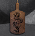 Snake Oil cutting board by CamiThunderInk, an original pyrography piece on a recycled wood cutting board showing a snake wrapped around an apothecary bottle