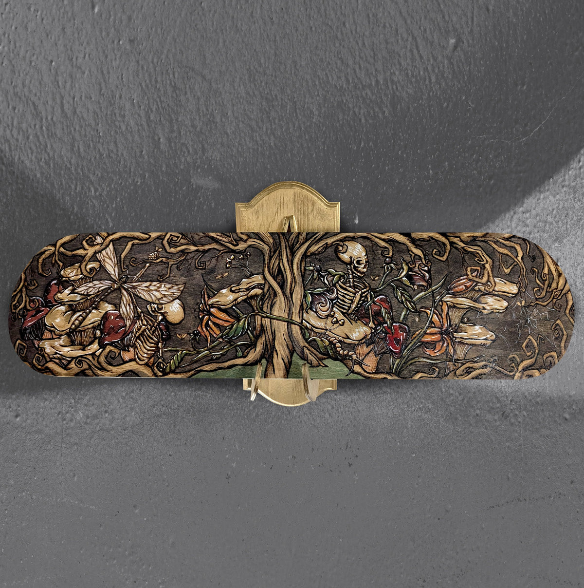 Another view of Tree of the Afterlife by CamiThunderInk, an original pyrography and watercolor painting on the underside of a maple skateboard deck showing a skeletal figure among mushrooms, lilies, and spiders
