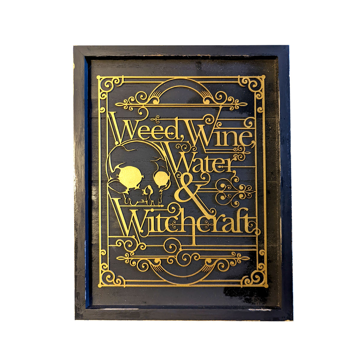 Another view of Weed, Wine, Water and Witchcraft by CamiThunderInk, gold laser cut Art Deco lettering with two witch silhouettes and scrollwork borders on a black painted wood frame